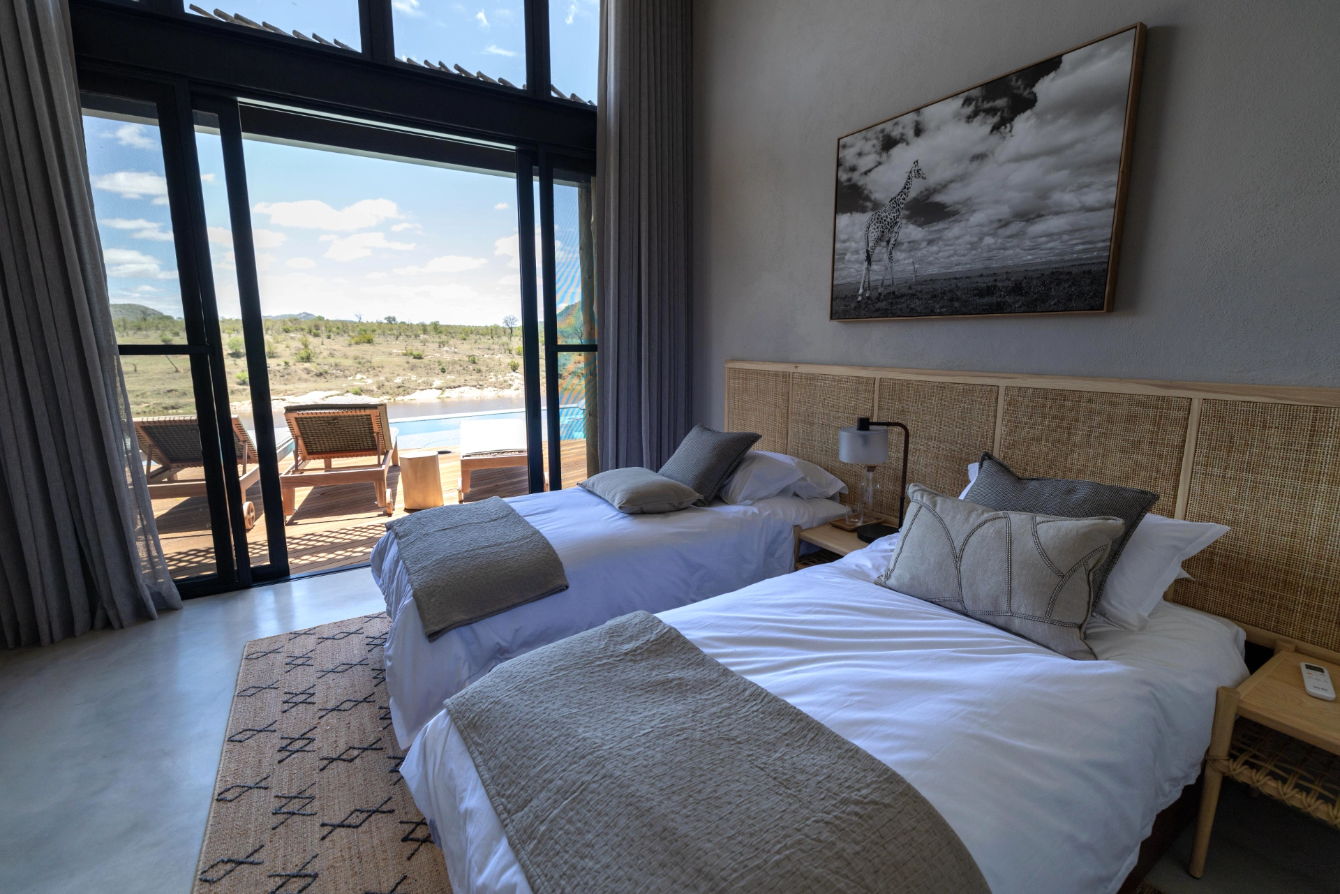 Twin bedroom at Izakithi River Villa with large sliding windows opening to the deck, sun loungers and pool overlooking the Crocodile River.