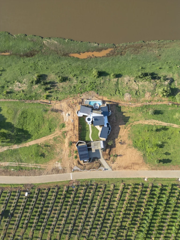 Aerial view of Izakithi River Villa along the riverbank, surrounded by greenery.