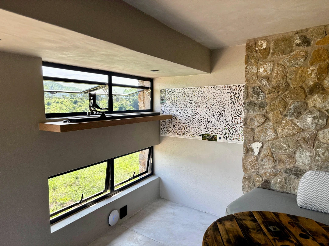 Espace intérieur lumineux avec grandes ouvertures sur l’extérieur, offrant une vue dégagée sur la nature, illustrant un environnement calme et isolé.